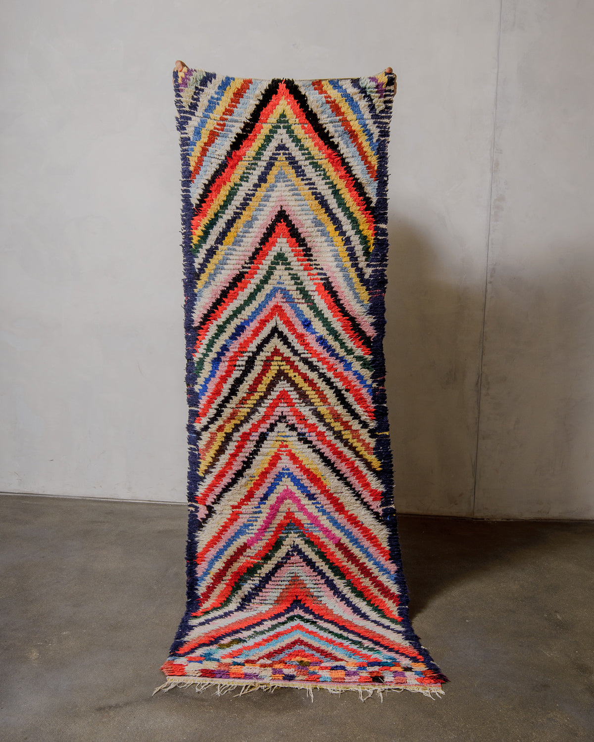 Colourful herringbone patterned rug against a neutral wall.